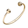 Brazalete tipo cuff con placas circulares en los extremos, decoradas con relieve central y borde tipo greca.