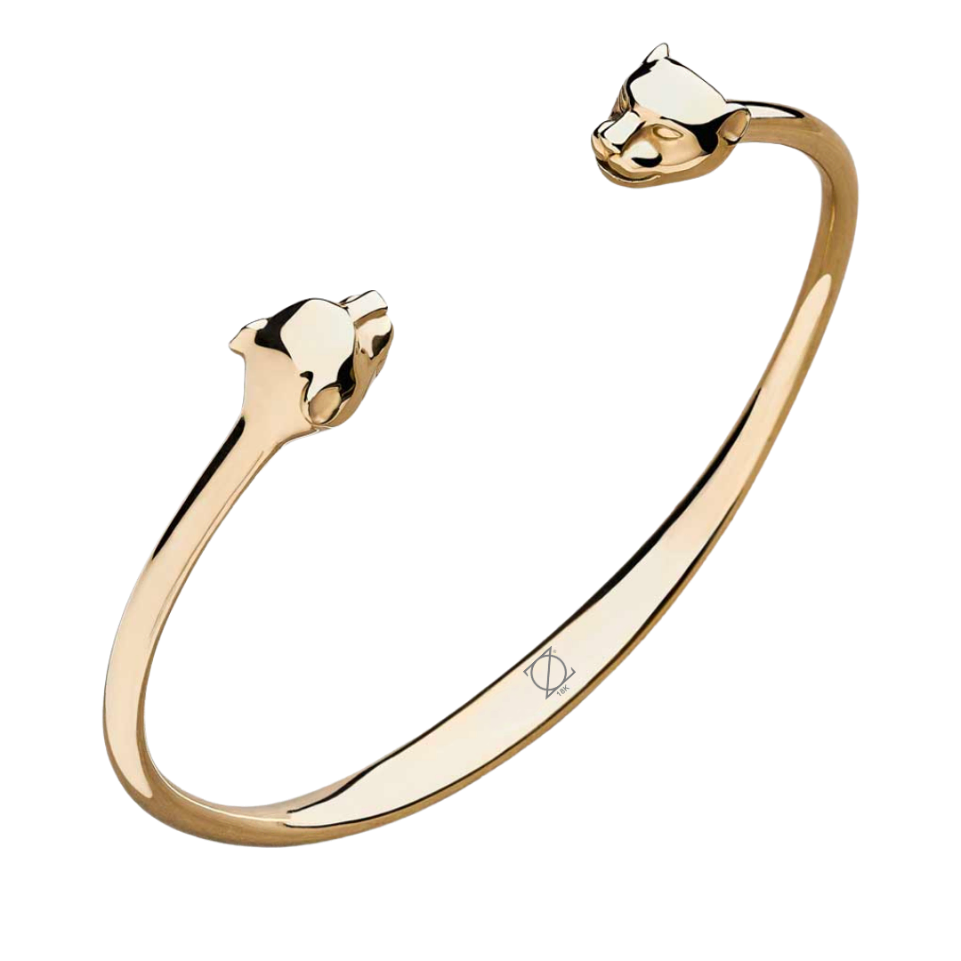 Brazalete rígido tipo cuff con terminaciones en forma de cabeza de pantera, pulido espejo y diseño abierto para ajuste cómodo.