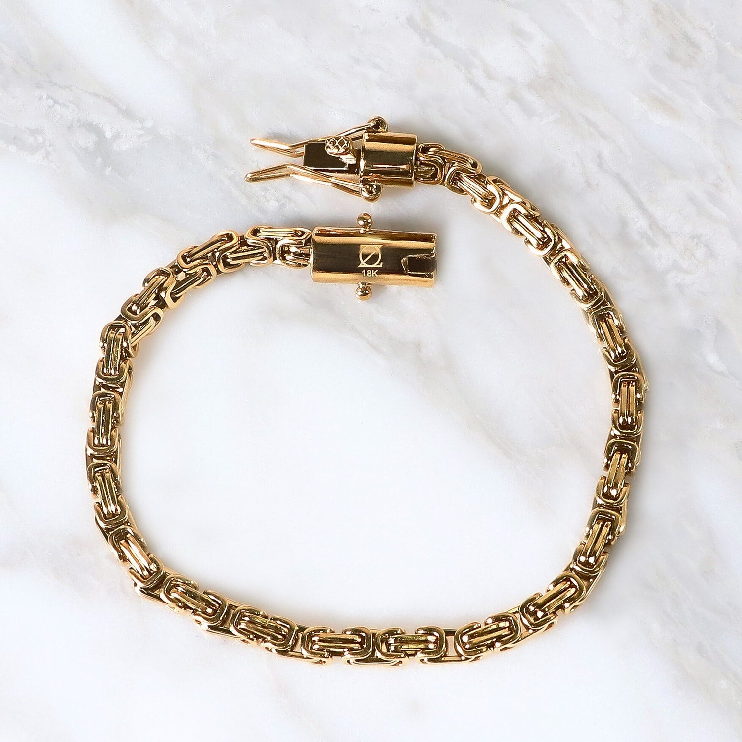 Pulsera Eredità Aurea  6mm en Oro laminado 18K. Su diseño se distingue por su trama sólida y continua, creando una silueta firme que proyecta presencia definida sobre la muñeca. Broche tubo para mayor firmeza.
Descúbrela en distintos tamaños y presentación.
Di Vogel Joyería Premium Chile